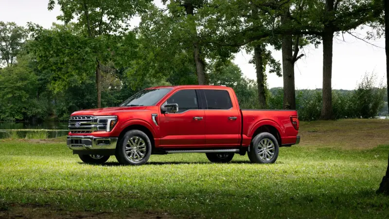 Red 2027 Ford F-150 Lariat SuperCrew parked on grass, side view