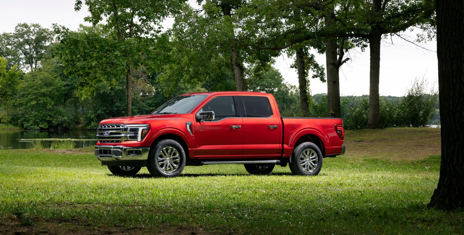 Red 2027 Ford F-150 Lariat SuperCrew parked on grass, side view
