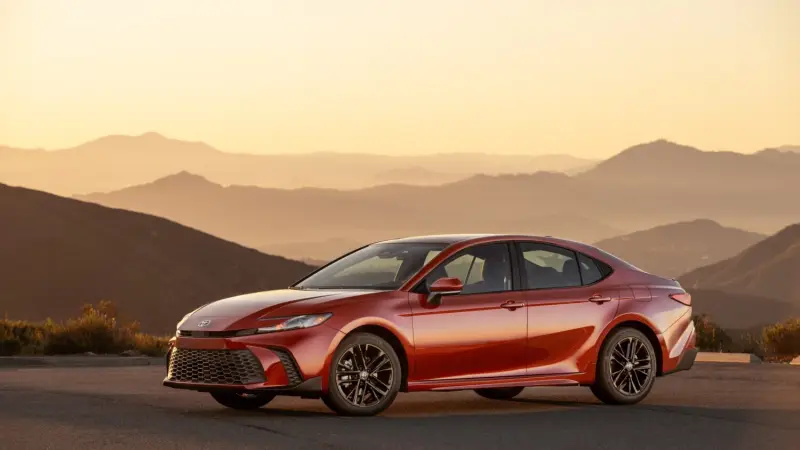 Red 2026 Toyota Camry SE AWD parked on a mountain road at sunset