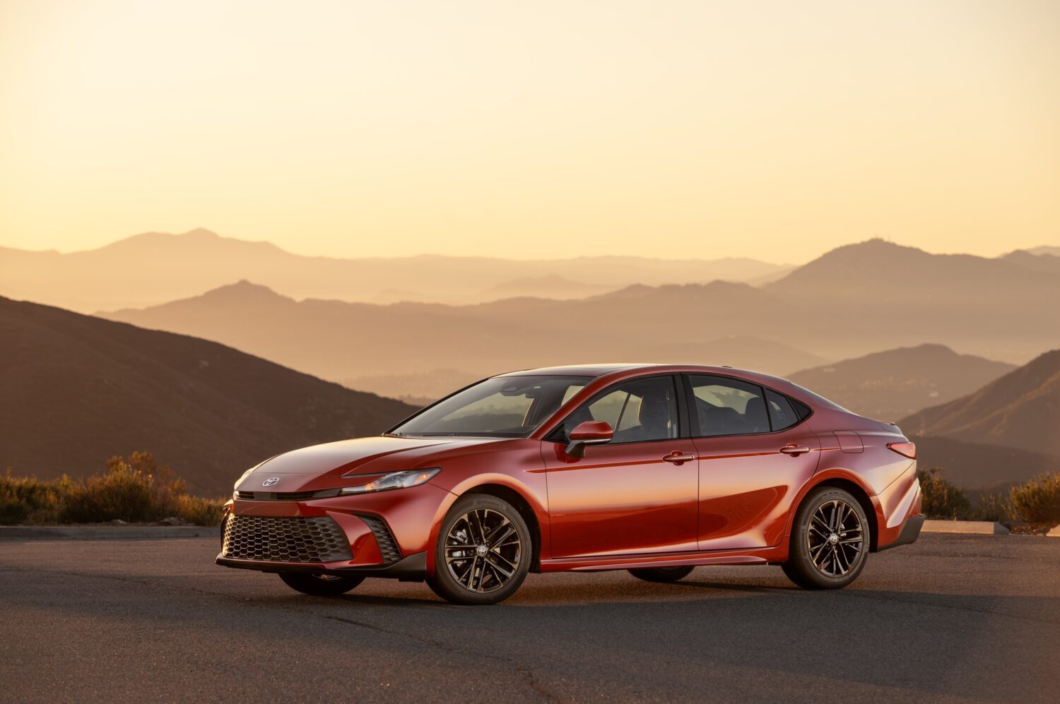 Red 2026 Toyota Camry SE AWD parked on a mountain road at sunset