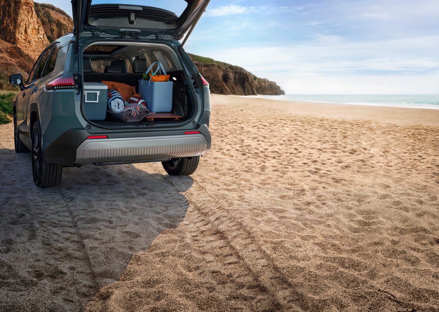 2026 Toyota RAV4 Limited with the tailgate open on a beach, cargo area loaded with camping gear